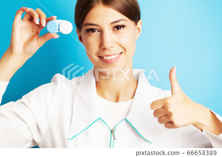 The ophthalmologist holds a container with contact lenses near the eyes The ophthalmologist holds a container with contact lenses near the eyes 66658389