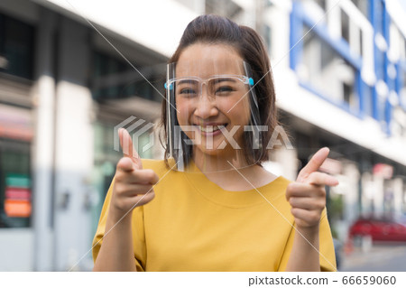 Portrait happy woman wile wearing a face shield Portrait happy woman wile wearing a face shield 66659060