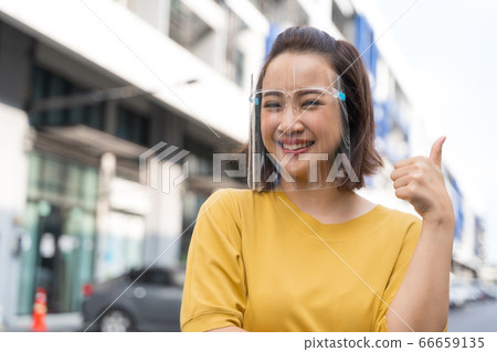 Portrait happy woman wile wearing a face shield for protection from cold and flu and viruses. Young woman with face mask in the street. Woman wearing face mask because of air pollution in the city Portrait happy woman wile wearing a face shield for protection from cold and flu and viruses. Young woman with face mask in the street. Woman wearing face mask because of air pollution in the city 66659135