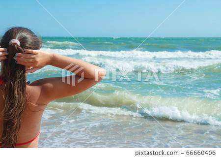 A young girl sits resting, sunbathing on the beach A young girl sits resting, sunbathing on the beach 66660406