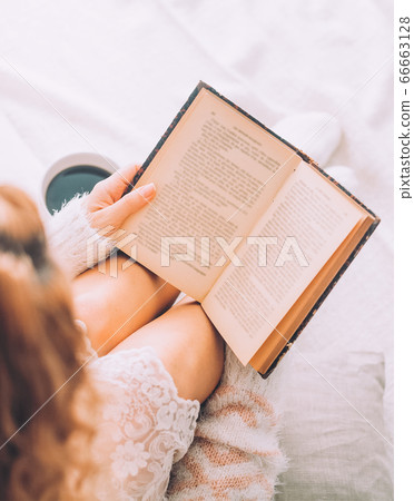 Young woman on the bed with old book and cup of Young woman on the bed with old book and cup of 66663128