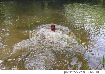 brunette swims in the pond, girl swims in the 66664013