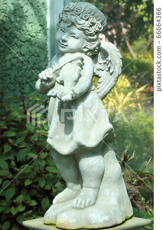 little angel statue isolated in the flower garden 66664366