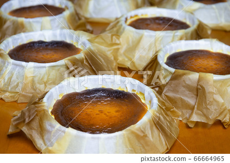 Spanish Dessert Basque burnt cheese on parchment paper on table. 66664965