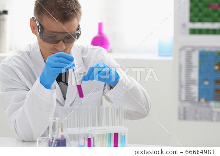 A male chemist holds test tube of glass in his hand overflows a liquid solution A male chemist holds test tube of glass in his hand overflows a liquid solution 66664981