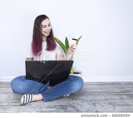 Young woman sitting on floor holding laptop Young woman sitting on floor holding laptop 66666094