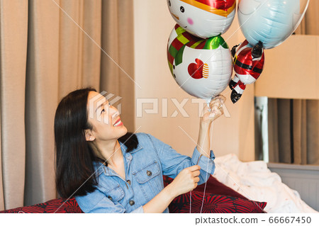 Happy woman with smile holding balloon as a present for special day at home. 66667450