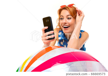 surprised girl leans on an inflatable swimming ball and reads messages on the phone on a white 66669573