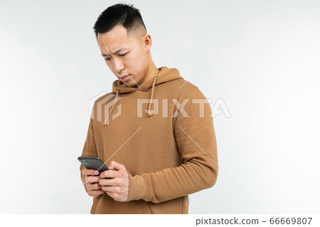 portrait of an asian man in a casual hoodie with a smartphone in his hands on a white background 66669807