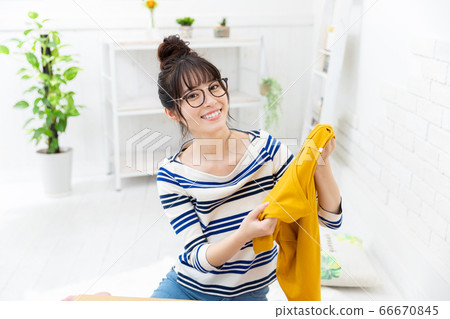 A woman preparing to sell clothes that are no longer used online A woman preparing to sell clothes that are no longer used online 66670845