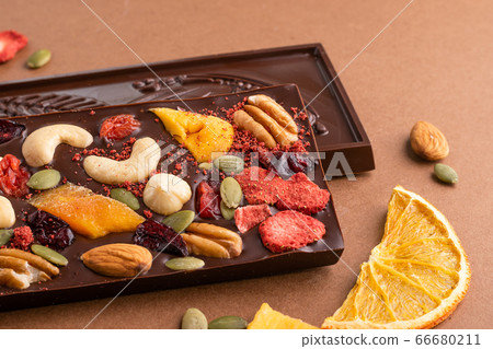 Chocolate dark Belgian bar with the addition of fruit nuts on brown background. Dessert food concept. Chocolate dark Belgian bar with the addition of fruit nuts on brown background. Dessert food concept. 66680211