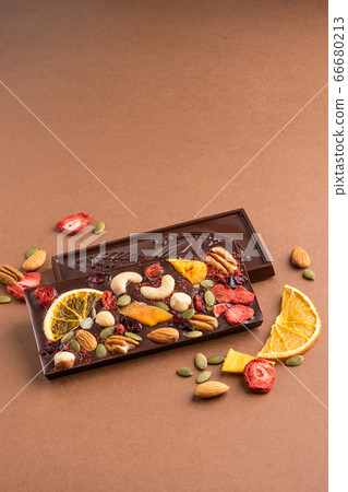 Chocolate dark Belgian bar with the addition of fruit nuts on brown background. Dessert food concept. 66680213