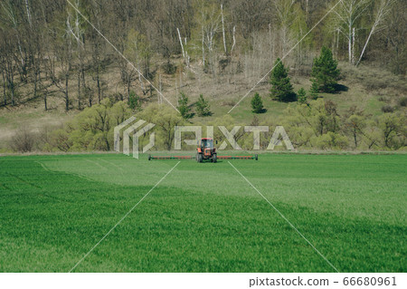 The tractor is working on a green spring field. The tractor is working on a green spring field. 66680961
