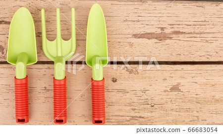 Garden tools of green color lie on the painted boards of the bench 66683054