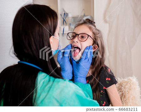 A female doctor carefully examines the throat of a small patient and takes a smear of mucosa for analysis. 66683211