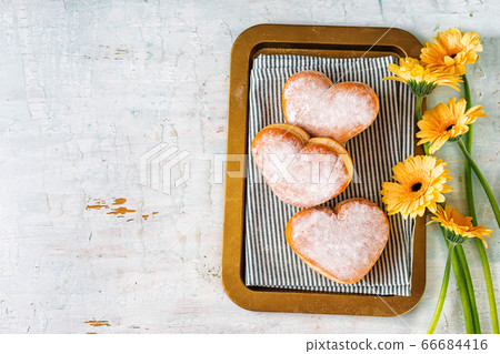 Top view of heart-shaped donuts in a tray with flowers Top view of heart-shaped donuts in a tray with flowers 66684416