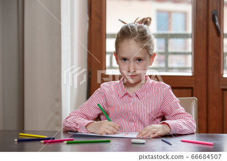 Portrait of a blond hair school girl, sitting at desk with pencils, drawing, looking at the camera 66684507