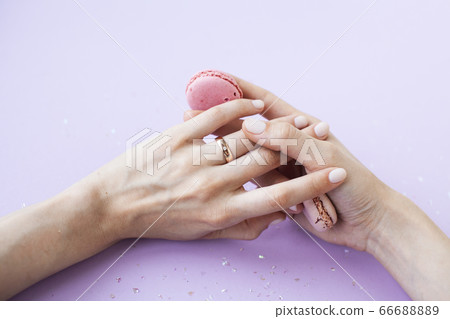 pretty perfect woman hands with white manicure and little flowers on colorful lilac background, green leaf spa concept pretty perfect woman hands with white manicure and little flowers on colorful lilac background, green leaf spa concept 66688889