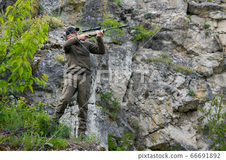 Male with a gun in hunting period 66691892