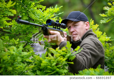 Male with a gun in hunting period 66691897