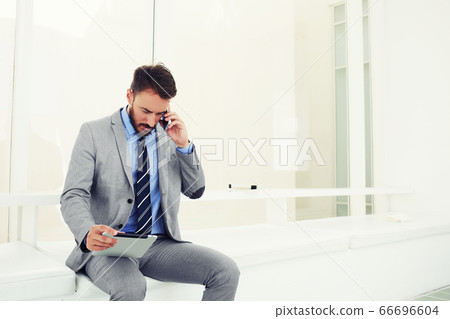 Smart male professional worker using touch pad while standing in office space 66696604