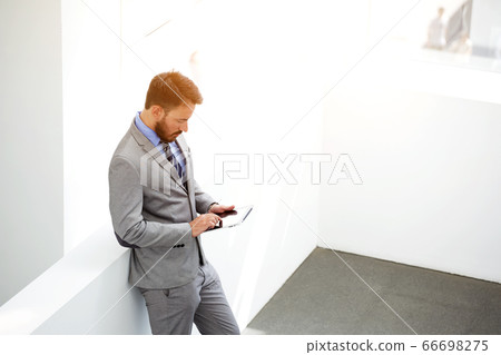 Half length portrait of rich businessman holding portable digital tablet during work break in hallway 66698275