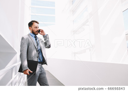 Half length portrait of rich businessman holding portable digital tablet during work break in hallway Half length portrait of rich businessman holding portable digital tablet during work break in hallway 66698843