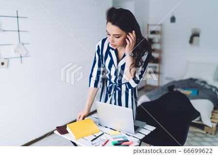 Young attractive female touching hair and using notebook 66699622