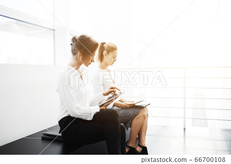 confident women entrepreneurs reading news by using digital tablet and cell telephone 66700108