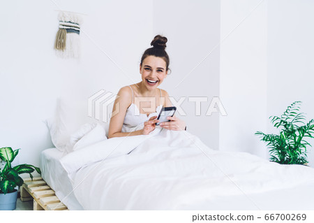 Laughing female having rest on bed in morning time Laughing female having rest on bed in morning time 66700269
