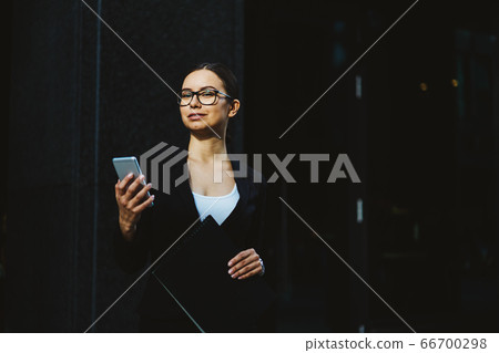 Young business woman in a black skirt and jacket on the street near the office building 66700298