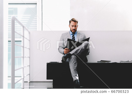 Handsome male manager in suit speaking on cell telephone during work break Handsome male manager in suit speaking on cell telephone during work break 66700323