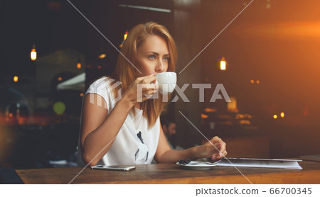 Young charming woman posing while sitting in cafe during coffee break, Young charming woman posing while sitting in cafe during coffee break, 66700345