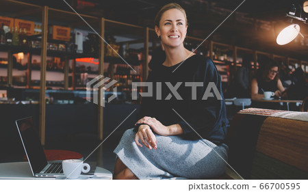 Beautiful female keyboarding on portable net-book while relaxing in coffee shop during free time 66700595