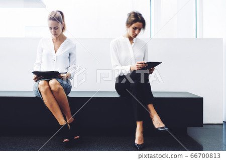confident women entrepreneurs reading news by using digital tablet and cell telephone 66700813