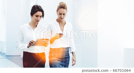 confident women entrepreneurs reading news by using digital tablet and cell telephone confident women entrepreneurs reading news by using digital tablet and cell telephone 66701064