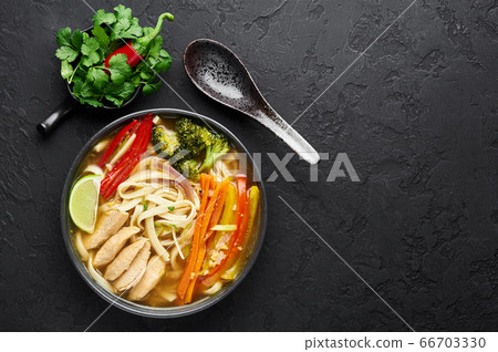 Chicken Thukpa in black bowl at dark slate background. Chicken Thukpa is Tibetan cuisine noodle soup Chicken Thukpa in black bowl at dark slate background. Chicken Thukpa is Tibetan cuisine noodle soup 66703330