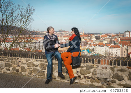 A man and a woman hold hands and sit on the observation deck of Visegrad. A man and a woman hold hands and sit on the observation deck of Visegrad. 66703838