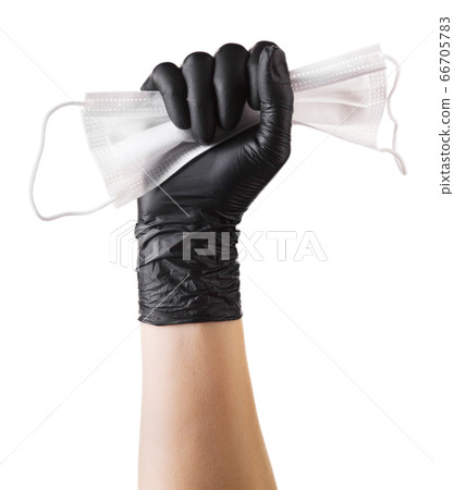 Hand in black gloves holding disposable face mask 66705783