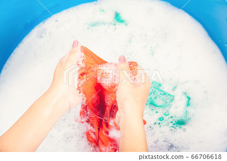 Woman use hands washing color clothes in basin Woman use hands washing color clothes in basin 66706618
