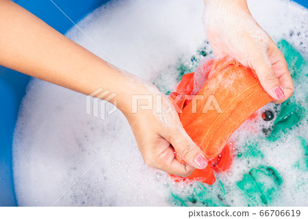 Woman use hands washing color clothes in basin Woman use hands washing color clothes in basin 66706619
