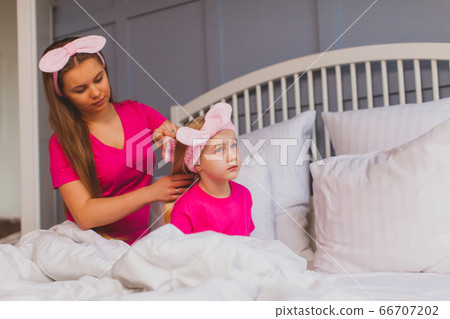 Young mother is combing her little daughters hair Young mother is combing her little daughters hair 66707202