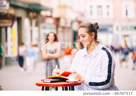 Woman doing work sitting in the street cafe 66707317