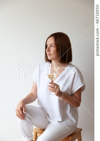 Caucasian brunette girl sommelier holding glass of white wine Caucasian brunette girl sommelier holding glass of white wine 66710050
