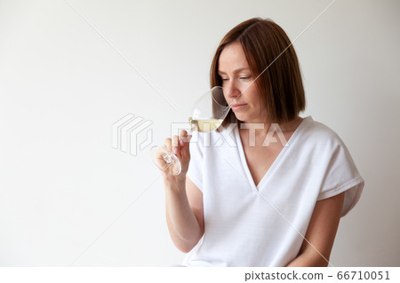 Caucasian brunette girl sommelier holding glass of white wine Caucasian brunette girl sommelier holding glass of white wine 66710051