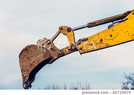 A close-up excavator loads soil into the bucket 66710074