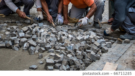 Team Of Construction Workers Building Pavement With Cobblestones 66711285