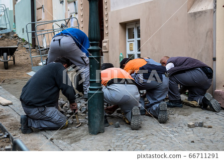 Team Of Construction Workers Building Pavement With Cobblestones 66711291