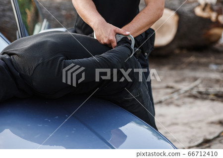A police officer arrested the offender in a mask with a stolen car and handcuffed him on the hood of the car. 66712410
