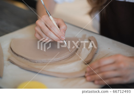 Close-up of a master potter, clay cutting special tool. Female artist cutting with a wooden loop tool. Close-up of a master potter, clay cutting special tool. Female artist cutting with a wooden loop tool. 66712493